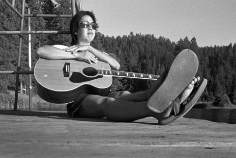 Brad Shirakawa sitting on the dock with a guitar (ddr-densho-336-1937)