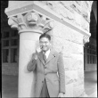 Man standing by carved stone pillar smoking a pipe (ddr-densho-426-2154)
