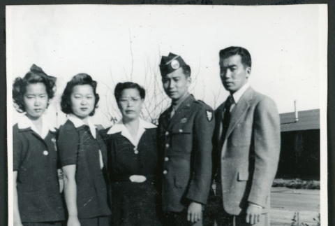 Photograph of five people, including an army soldier, posing in front of the Manzanar barracks (ddr-csujad-47-204)