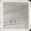 Woman at a beach lifting seaweed (ddr-densho-321-328)