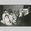 Staged holiday photo of Sakura children listening to Chester Sakura read from book titled: Joys of Christmas (ddr-densho-523-195)