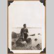 Man seated on rocks by the water (ddr-densho-542-152)