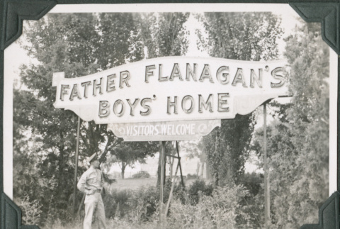Man standing below sign:  Father Flanagan's Boys' Home (ddr-ajah-2-394)