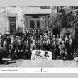 Group photo outside building, holding banner in Japanese (ddr-ajah-3-186)