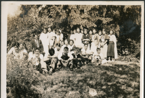 Group of men and women on grassy hill by trees (ddr-densho-483-565)