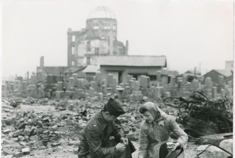 Ted Akimoto and a woman look at pieces of rubble from blast (ddr-densho-299-148)