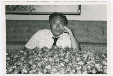 Man poses with pile of fortune cookies (ddr-densho-499-52)