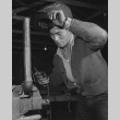 Former California mechanic Chester Ishii repairing piece of farm machinery at Rohwer incarceration camp (ddr-csujad-14-25)
