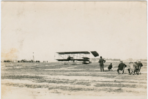 Photo of men watching flight of early bi-plane (ddr-densho-355-12)