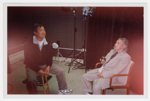 Tom Ikeda speaking to a narrator in the recording studio (ddr-densho-506-33)