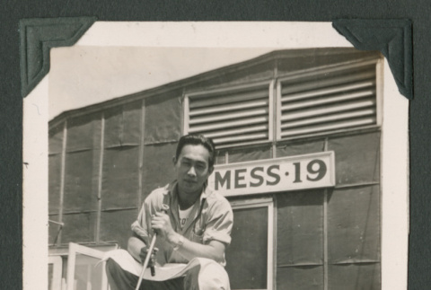 Man atop log pile outside Mess 19 (ddr-densho-471-58)