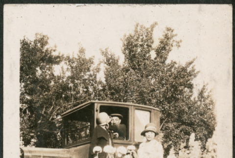 Three people by car, one looking away (ddr-densho-293-77)