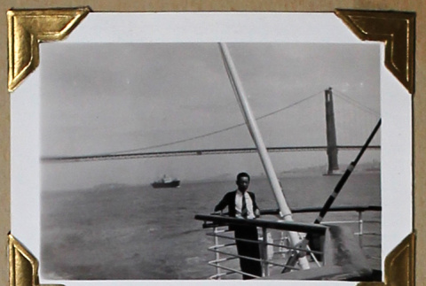 Man poses on boat in front of the Golden Gate Bridge (ddr-densho-404-291)
