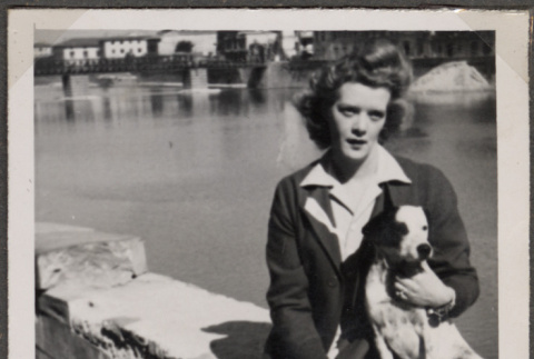 Woman holding dog sitting on wall by river (ddr-densho-466-114)