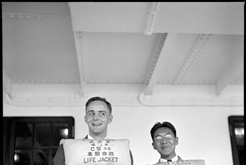 Two men wearing life vests on board ship (ddr-densho-426-267)