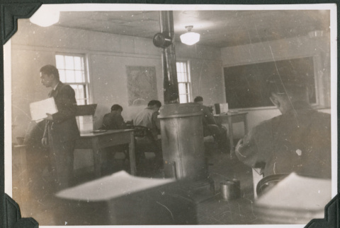 Classroom with desks and wood burning stove in center (ddr-ajah-2-429)