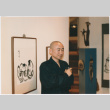 A man in an art show with sumi-e paintings (ddr-densho-377-313)