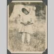 Girl holding an apple standing in field (ddr-densho-483-521)
