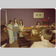 Three girls standing by piano (ddr-densho-426-134)