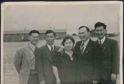 Four men and a woman with barracks in background (ddr-densho-523-140)