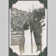 Man with rifle standing next to sign in snow (ddr-ajah-2-288)