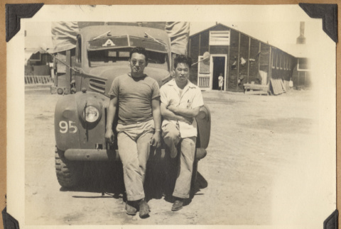 Two men lean on a truck (ddr-densho-542-148)