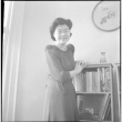 Tomoye (Nozawa) Takahashi standing by bookshelf (ddr-densho-426-2025)