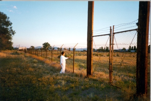 Former camp inmate next to a barbed wire fence (ddr-densho-62-2)