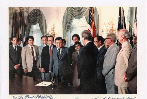 Group at desk in White House, signing of Commission of Wartime Relocation and Internment of Citizens Act into law (ddr-densho-393-24)