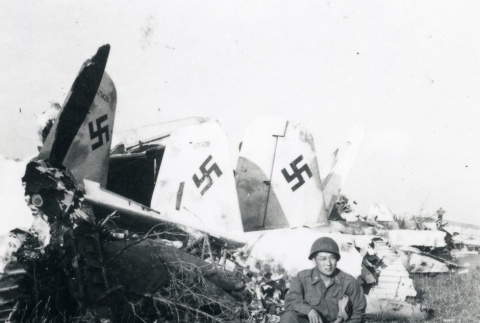 522nd soldier kneeling next to downed German planes (ddr-densho-22-109)