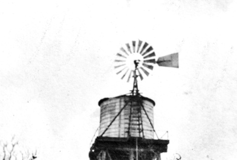 Man and girl standing by windmill and water tank (ddr-ajah-6-572)