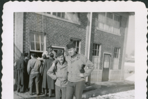 Two men, arm-in-arm, outside building with group in background (ddr-densho-434-485)