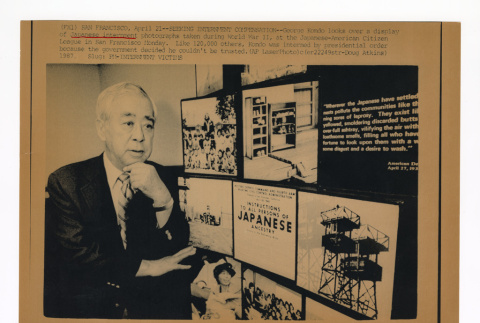 George Kondo near a display of photographs taken at incarceration camps during World War II (ddr-csujad-52-14)