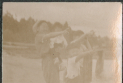Woman and three children standing beach, pointing (ddr-densho-523-99)