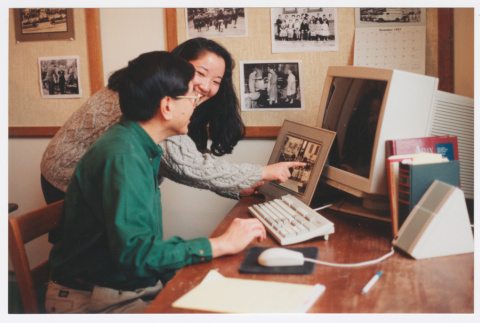 Becky Fukuda and staff member looking at photo at computer workstation (ddr-densho-506-67)