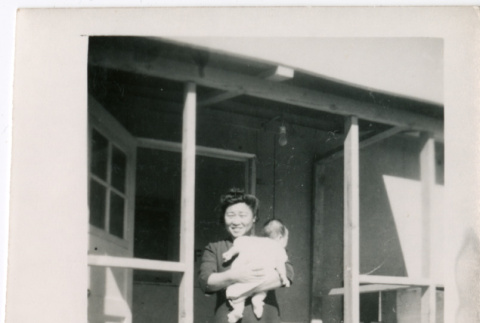 Woman holding baby in doorway of barracks (ddr-densho-329-1327)
