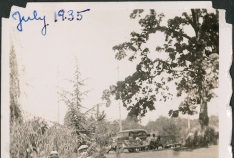 Three men standing on rocks next to pond in Japanese Garden (ddr-densho-483-561)